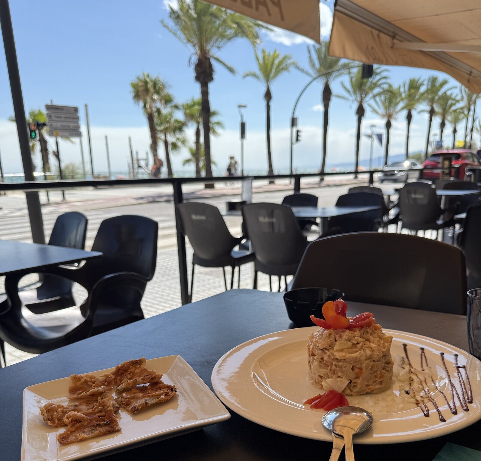 Tapas en la terraza, con las palmeras del paseo y el mar al fondo