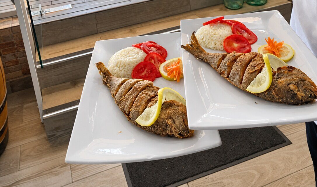 Pescado entero con arroz blanco, tomate y limón, recién salido de cocina
